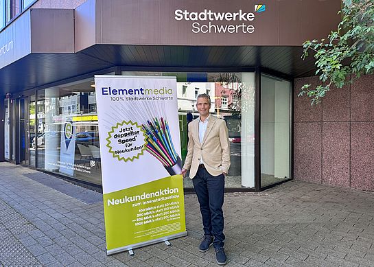 Ein Mitarbeitet der Elementmedia steht vor dem Kundenzentrum der Stadtwerke Schwerte und bewirbt eine Neukundenaktion für den verkaufsoffenen Sonntag in Schwerte